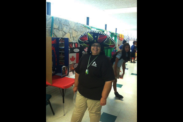 Teacher wearing sombrero standing in front of project presentations