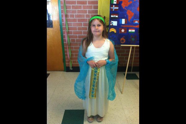 Student wearing traditional heritage clothing standing in front of project presentation