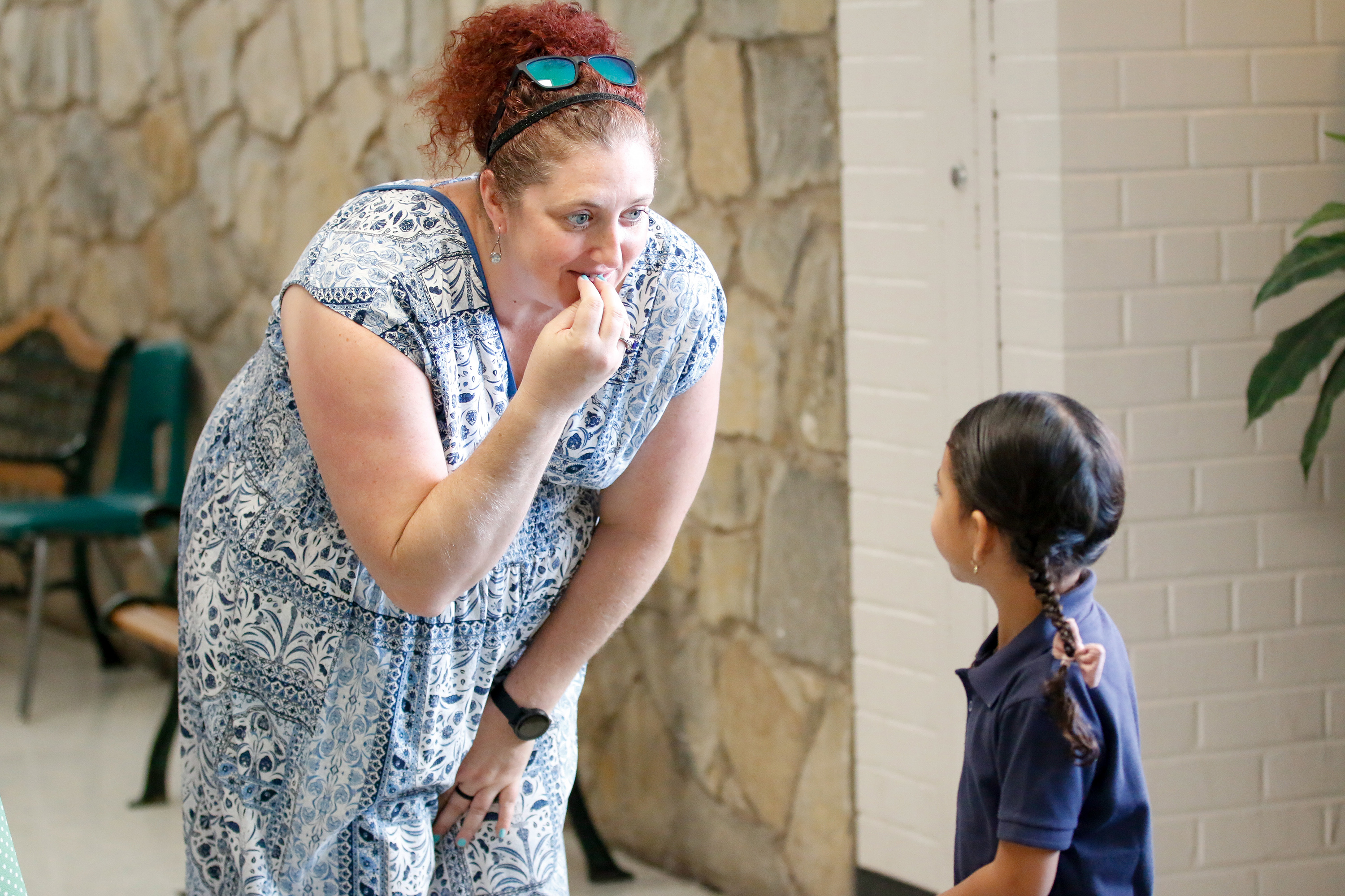 A teacher crouches down to say hi to a student