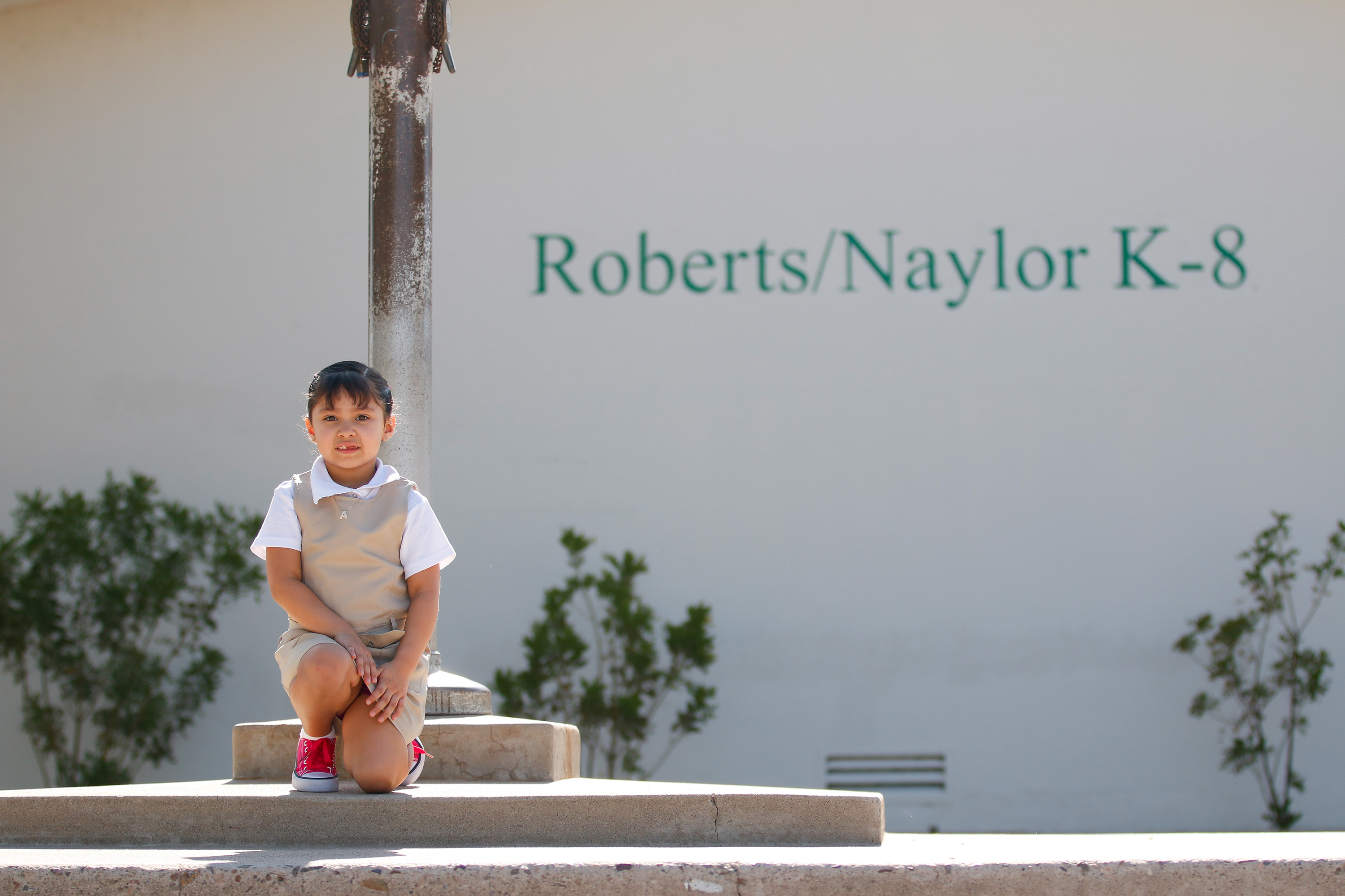 A little girl poses in front of the flagpole on the second day of school