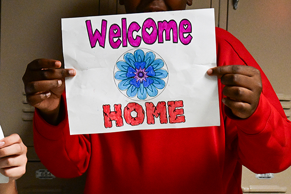 A boy holds up a Welcome Home sign