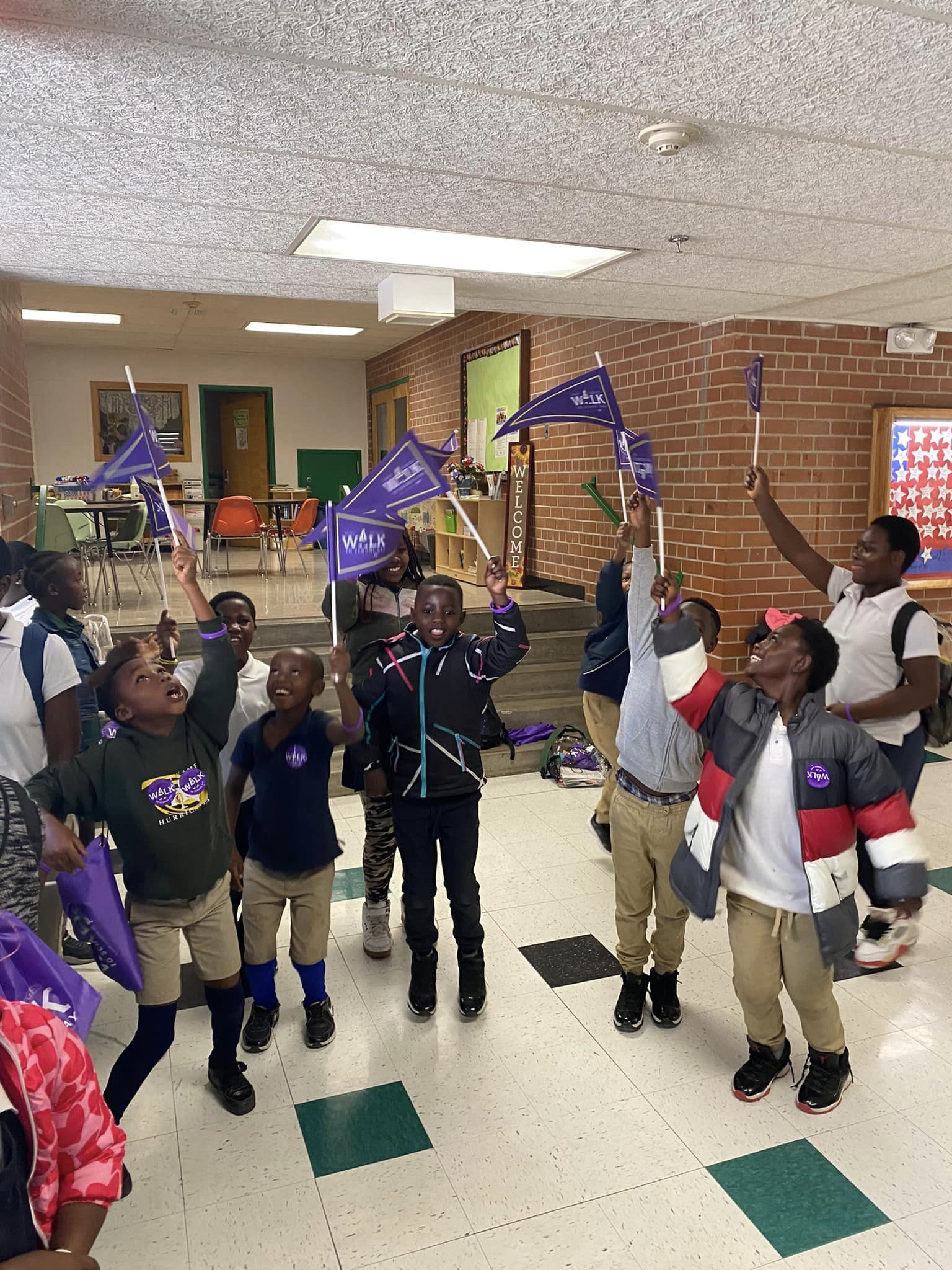 Students hold up their purple Ruby Bridges Day pennants