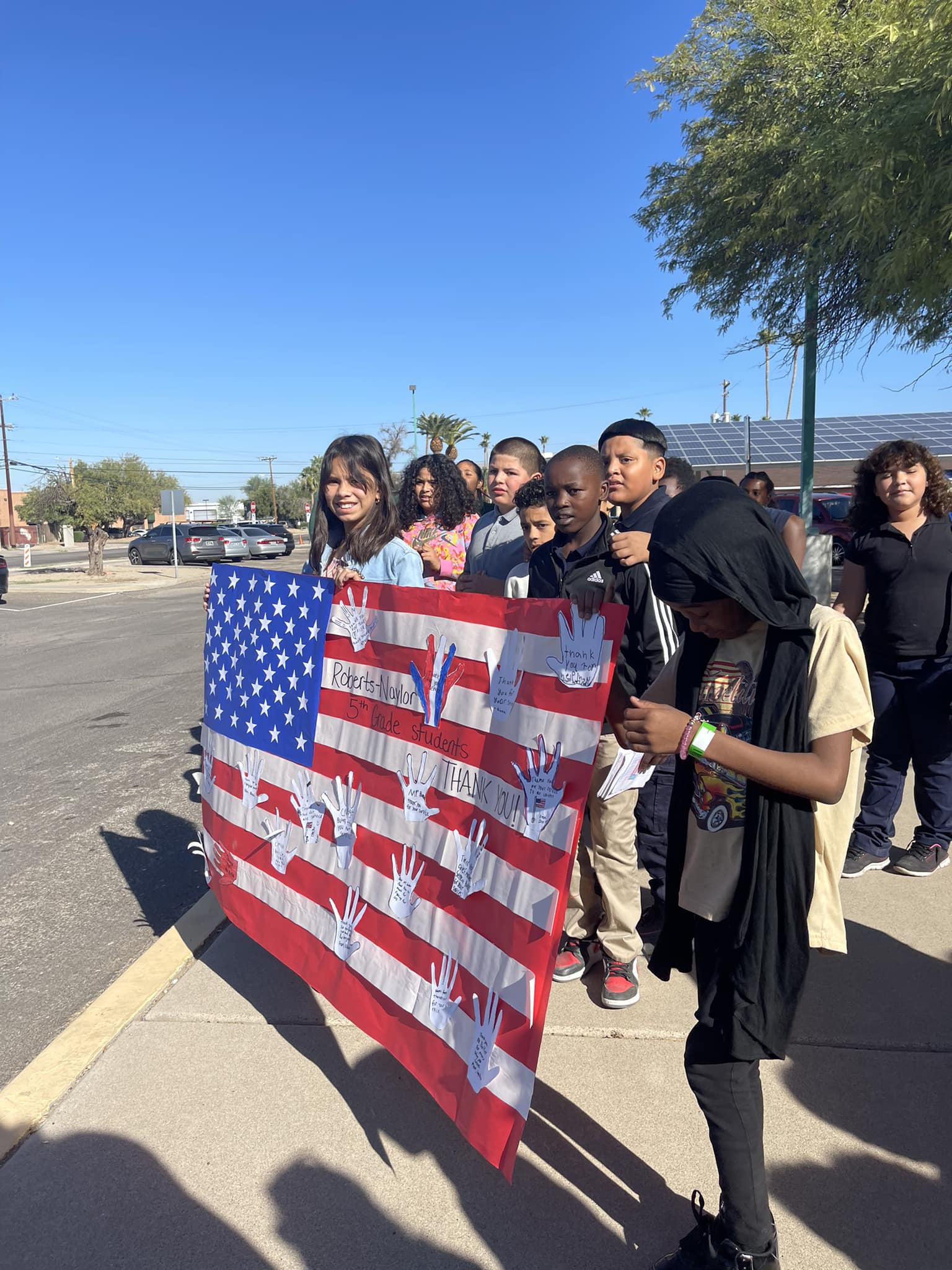 Students hold up their Veterans Day flag poster that they created