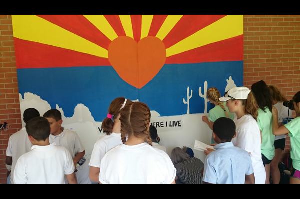 students gathered together in front of mural outside 