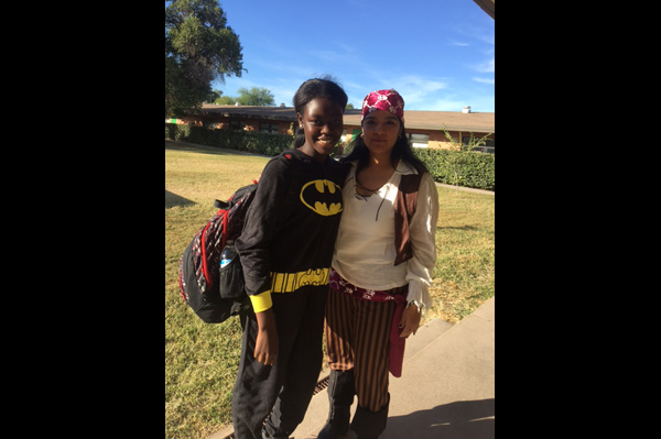 2 students dressed in Halloween costumes stand outside of school building