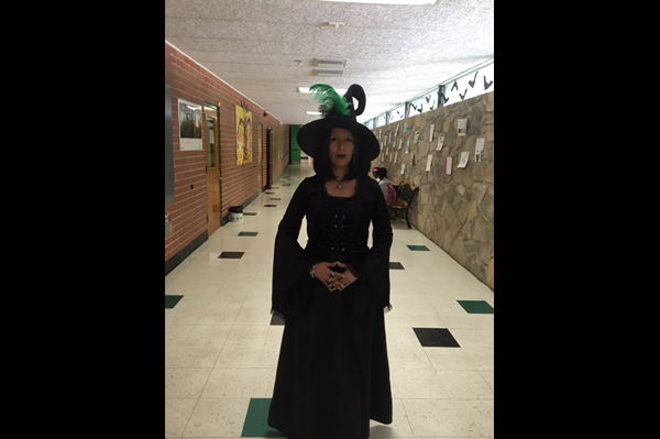 Teacher in a witch costume stands in the hallway