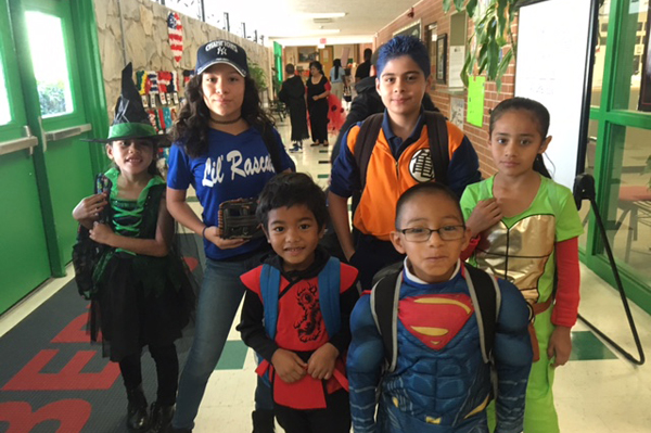Students dressed in Halloween costumes gathered together in hallway in front of door