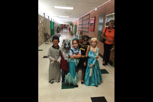 Students dressed in Halloween costumes gathered together standing in hallway