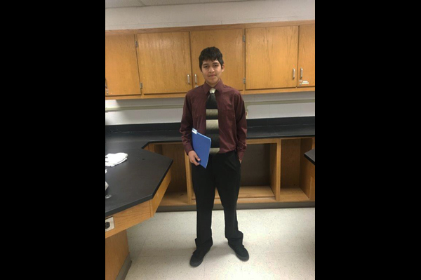 Student holding folder standing in classroom
