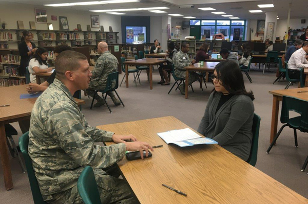 Student sitting at table talking with soldier