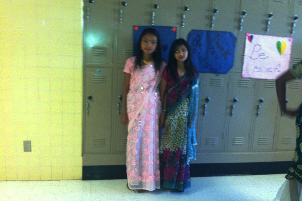 2 students wearing traditional heritage clothing standing in front of lockers