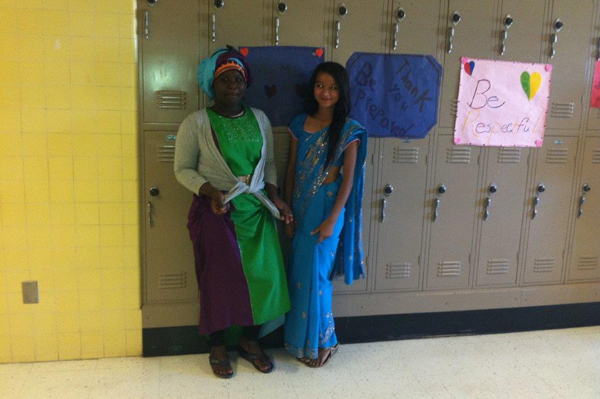 2 students dressed in traditional heritage clothing standing in front of lockers