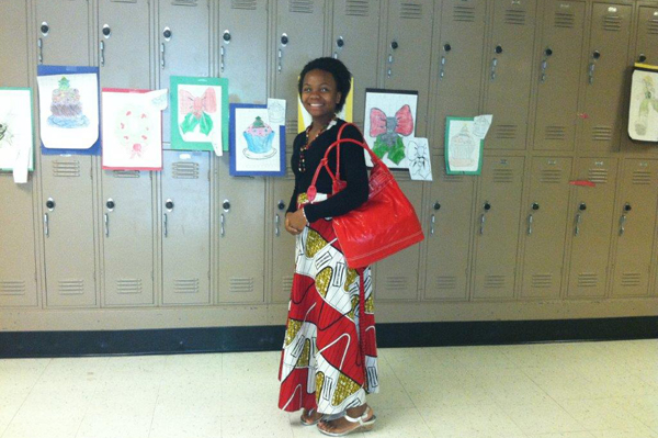 Student standing in front of lockers dressed in traditional heritage clothing with a purse