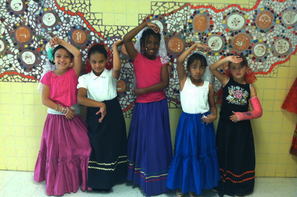 5 students dressed in traditional heritage clothing dancing