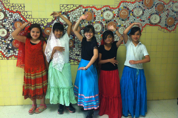 5 Students dressed in traditional heritage clothing dancing