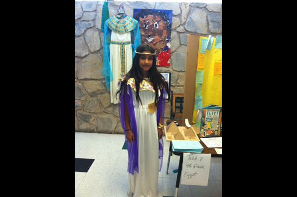 Student dressed in traditional heritage clothing standing in front of project presentation
