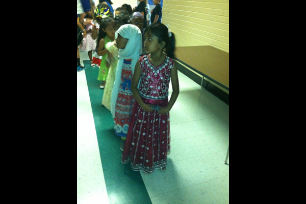 Students wearing traditional heritage clothing lined up in a line in the hall