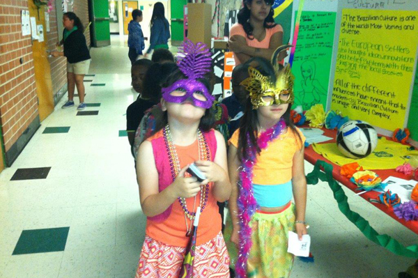 Students dressed up in masks, boas, and beaded jewelry lining up in hallway